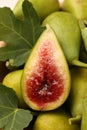 Cut and whole fresh green figs with leaves as background, closeup Royalty Free Stock Photo