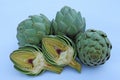 Cut and whole fresh raw artichokes on light blue background, closeup Royalty Free Stock Photo