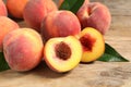 Cut and whole fresh ripe peaches with green leaves on wooden table, closeup Royalty Free Stock Photo