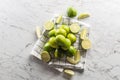 Cut and whole limes on a kitchen towel and a marble surface