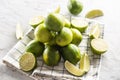 Cut and whole limes on a kitchen towel and a marble surface