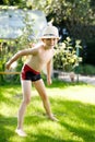 Cute active kid boy jumping in the garden on warm sunny summer day. Happy kid looking at the camera. Adorable child with