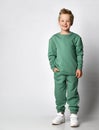 cute active little boy in trendy sports green clothes standing with hand in pocket showing emotions of happiness and Royalty Free Stock Photo