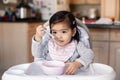 Cute adorable Asian Chinese kid girl sitting in high chair eating soup with spoon. Healthy eating for kids children. Toddler Royalty Free Stock Photo