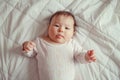 cute adorable Asian mixed race baby girl four months old lying on bed in bedroom looking in camera. Royalty Free Stock Photo