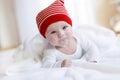 Cute adorable baby child with Christmas winter cap on white background. Happy baby girl or boy smiling and looking at Royalty Free Stock Photo