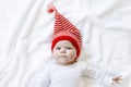 Cute adorable baby child with Christmas winter cap on white background. Happy baby girl or boy smiling and looking at Royalty Free Stock Photo