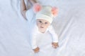 Cute adorable baby child with warm white and pink hat with cute bobbles. Happy baby girl learning crawl and looking at Royalty Free Stock Photo