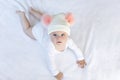 Cute adorable baby child with warm white and pink hat with cute bobbles. Happy baby girl learning crawl and looking at Royalty Free Stock Photo