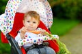 Cute adorable baby girl holding and eating fresh carrot. Beatuiful child having healthy snack. Baby girl sitting in pram Royalty Free Stock Photo