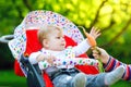 Cute adorable baby girl holding and eating fresh carrot. Beatuiful child having healthy snack. Baby girl sitting in pram Royalty Free Stock Photo