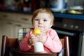 Cute adorable baby girl holding nursing bottle and drinking formula milk. First food for babies. New born child, sitting Royalty Free Stock Photo