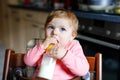 Cute adorable baby girl holding nursing bottle and drinking formula milk. First food for babies. New born child, sitting Royalty Free Stock Photo