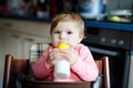 Cute adorable baby girl holding nursing bottle and drinking formula milk. First food for babies. New born child, sitting Royalty Free Stock Photo