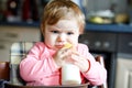 Cute adorable baby girl holding nursing bottle and drinking formula milk. First food for babies. New born child, sitting Royalty Free Stock Photo