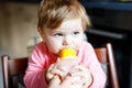 Cute adorable baby girl holding nursing bottle and drinking formula milk. First food for babies. New born child, sitting Royalty Free Stock Photo