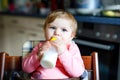 Cute adorable baby girl holding nursing bottle and drinking formula milk. First food for babies. New born child, sitting Royalty Free Stock Photo