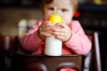 Cute adorable baby girl holding nursing bottle and drinking formula milk. First food for babies. New born child, sitting Royalty Free Stock Photo