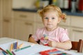 Cute adorable baby girl learning painting with pencils. Little toddler child drawing at home, using colorful felt tip Royalty Free Stock Photo