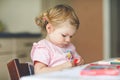 Cute adorable baby girl learning painting with pencils. Little toddler child drawing at home, using colorful felt tip Royalty Free Stock Photo
