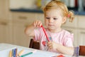 Cute adorable baby girl learning painting with pencils. Little toddler child drawing at home, using colorful felt tip Royalty Free Stock Photo