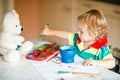 Cute adorable baby girl learning painting with water colors. Little toddler child drawing at home, using colorful Royalty Free Stock Photo