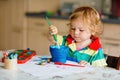 Cute adorable baby girl learning painting with water colors. Little toddler child drawing at home, using colorful Royalty Free Stock Photo