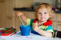 Cute adorable baby girl learning painting with water colors. Little toddler child drawing at home, using colorful Royalty Free Stock Photo