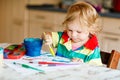 Cute adorable baby girl learning painting with water colors. Little toddler child drawing at home, using colorful Royalty Free Stock Photo