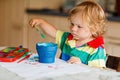 Cute adorable baby girl learning painting with water colors. Little toddler child drawing at home, using colorful Royalty Free Stock Photo