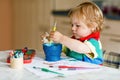 Cute adorable baby girl learning painting with water colors. Little toddler child drawing at home, using colorful Royalty Free Stock Photo