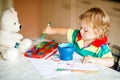 Cute adorable baby girl learning painting with water colors. Little toddler child drawing at home, using colorful Royalty Free Stock Photo