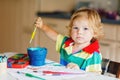 Cute adorable baby girl learning painting with water colors. Little toddler child drawing at home, using colorful Royalty Free Stock Photo