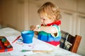 Cute adorable baby girl learning painting with water colors. Little toddler child drawing at home, using colorful Royalty Free Stock Photo