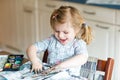 Cute adorable baby girl learning painting with water colors. Little toddler drawing at home, using colorful brushes Royalty Free Stock Photo