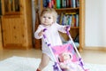 Cute adorable baby girl making first steps with doll carriage. Royalty Free Stock Photo