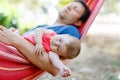 Cute adorable baby girl of 6 months and her father sleeping peaceful in hammock in outdoor garden Royalty Free Stock Photo