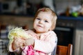 Cute adorable baby girl playing with first doll. Beautiful toddler child sitting in high chair at home. Happy healthy