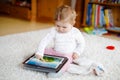 Cute adorable baby girl watching cartoons on tablet pc. Todder child at home touching on screen and playing educational Royalty Free Stock Photo