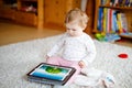 Cute adorable baby girl watching cartoons on tablet pc. Todder child at home touching on screen and playing educational Royalty Free Stock Photo