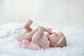 A child of 5 months is having fun alone,lying on a snow-white bed. Royalty Free Stock Photo