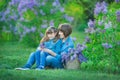 Cute adorable beautifull mother lady mom woman with brunette girl daughter in meadow of lilac purple bush.People in jeans wear. Royalty Free Stock Photo