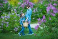 Cute adorable beautifull mother lady mom woman with brunette girl daughter in meadow of lilac purple bush.People in jeans wear. Royalty Free Stock Photo