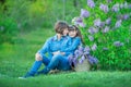 Cute adorable beautifull mother lady mom woman with brunette girl daughter in meadow of lilac purple bush.People in jeans wear. Royalty Free Stock Photo