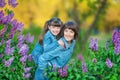 Cute adorable beautifull mother lady mom woman with brunette girl daughter in meadow of lilac purple bush.People in jeans wear. Royalty Free Stock Photo