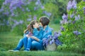 Cute adorable beautifull mother lady mom woman with brunette girl daughter in meadow of lilac purple bush.People in jeans wear. Royalty Free Stock Photo