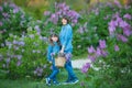 Cute adorable beautifull mother lady mom woman with brunette girl daughter in meadow of lilac purple bush.People in jeans wear. Royalty Free Stock Photo