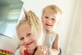 Cute adorable blond caucaian little sister hugging her toddler brother.couple of cheerful sibling playing indoor. Cute girl and Royalty Free Stock Photo