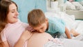 Cute adorable boy kissing and listening to big belly of his pregnant mother lying on bed. Concept of loving children and Royalty Free Stock Photo