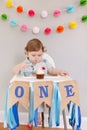 Cute adorable Caucasian baby boy celebrating his first birthday at home. Pensive child kid toddler sitting in high chair table Royalty Free Stock Photo